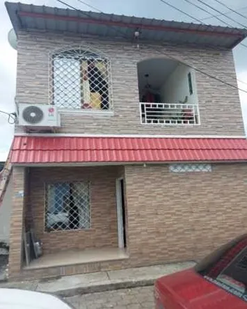 Casa de dos plantas en Daule con techo rojo, balcón y fachada revestida.